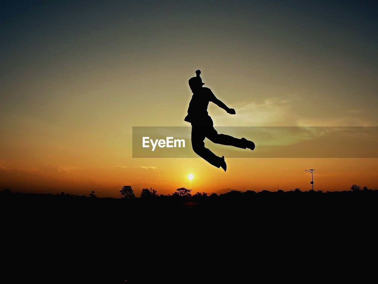 Silhouette man jumping against sky during sunset