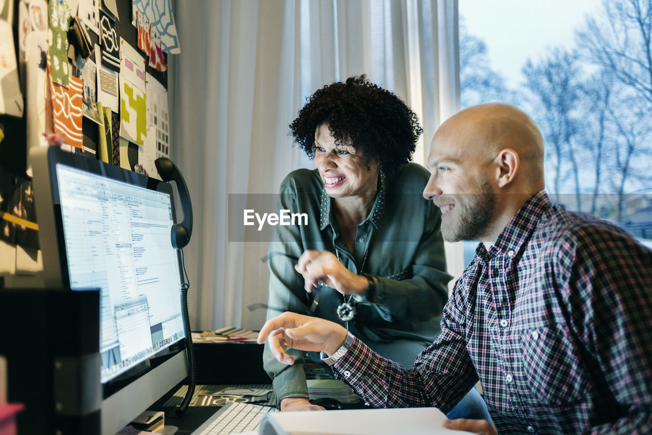 Happy business people working on computer in office