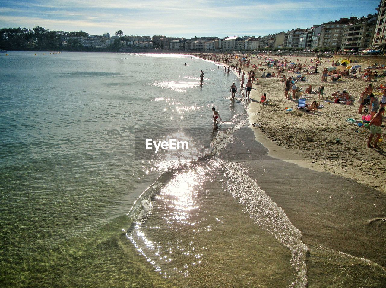 PEOPLE ON BEACH AGAINST SEA