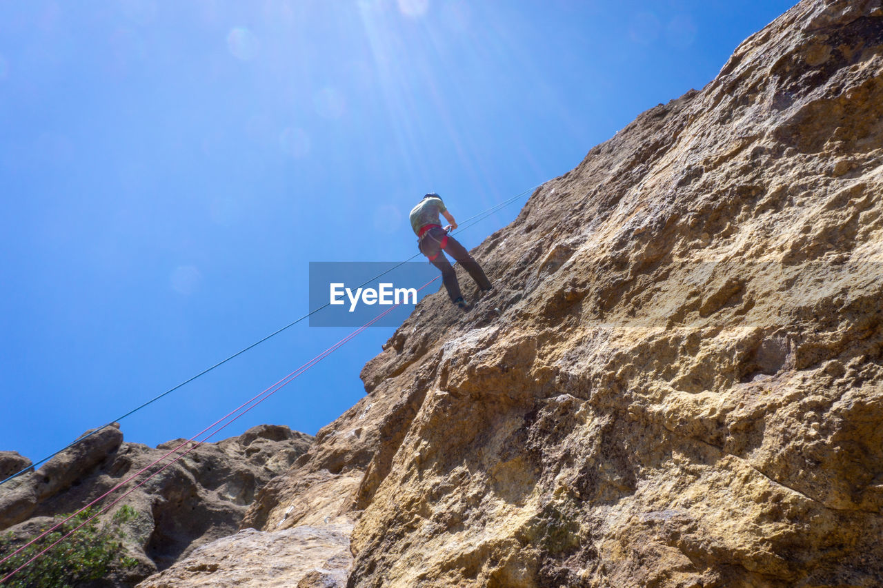 Low angle view of person on rock against sky