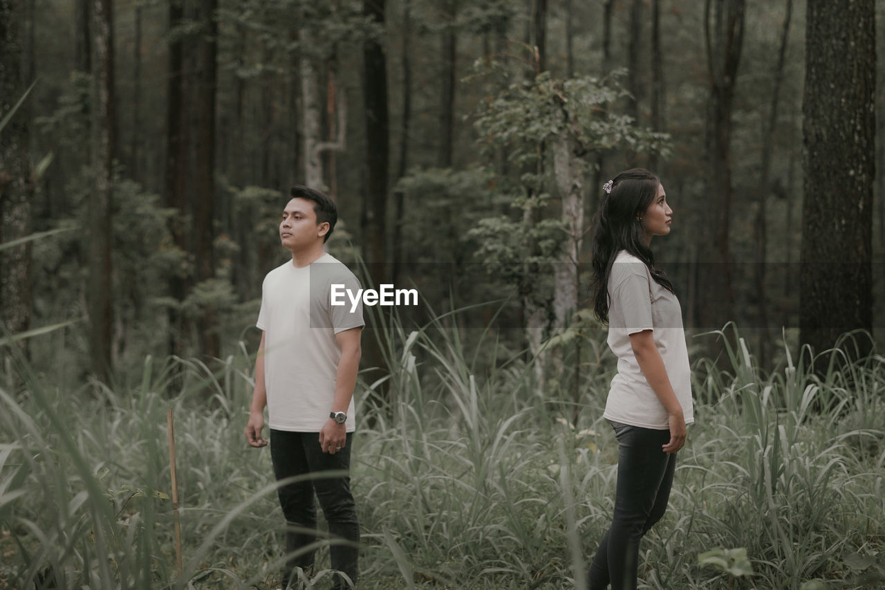 Side view of woman standing on field in forest