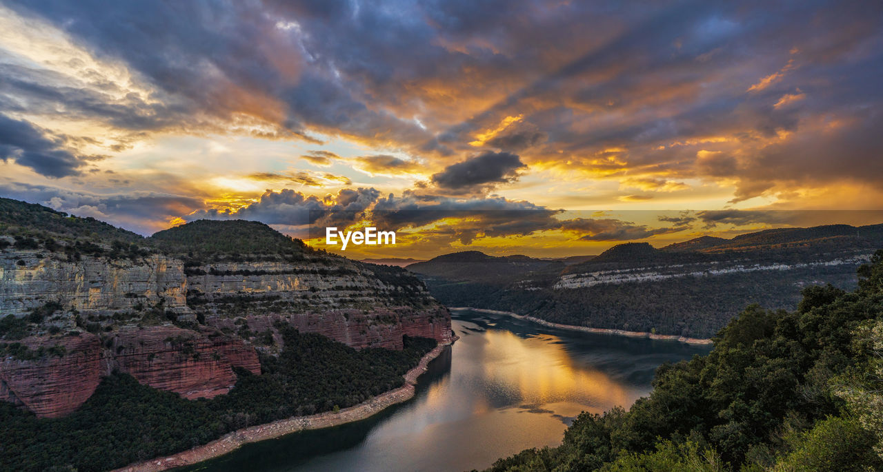 SCENIC VIEW OF RIVER AND MOUNTAINS AGAINST SKY AT SUNSET