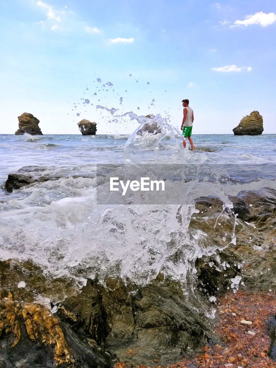 Waves splashing on rocks at beach against sky