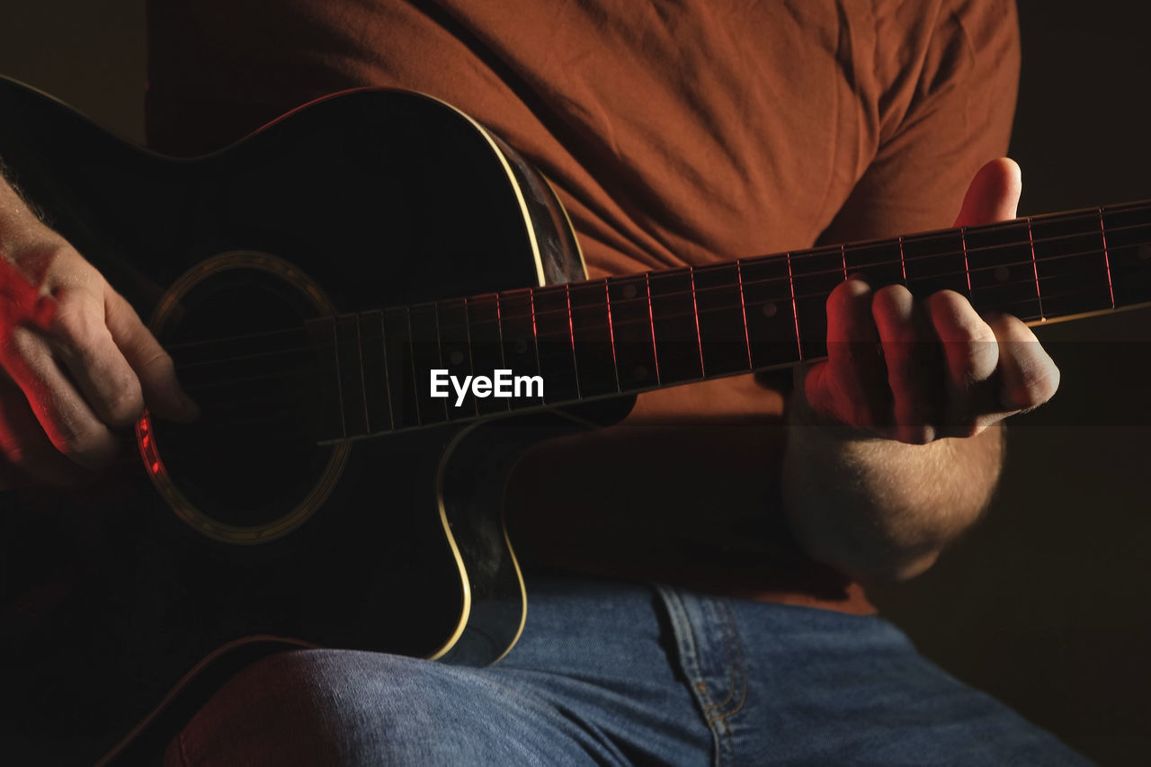 Man playing guitar chord. strumming acoustic guitar. male fingers and fretboard closeup. guitar neck