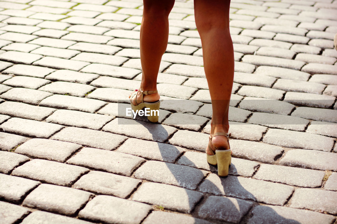 Low section of woman walking on footpath