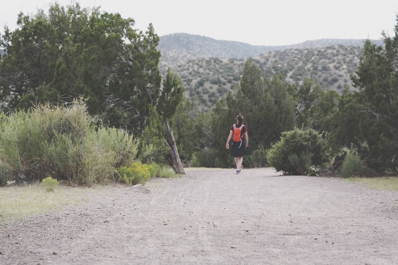 Rear view of woman walking on field against trees