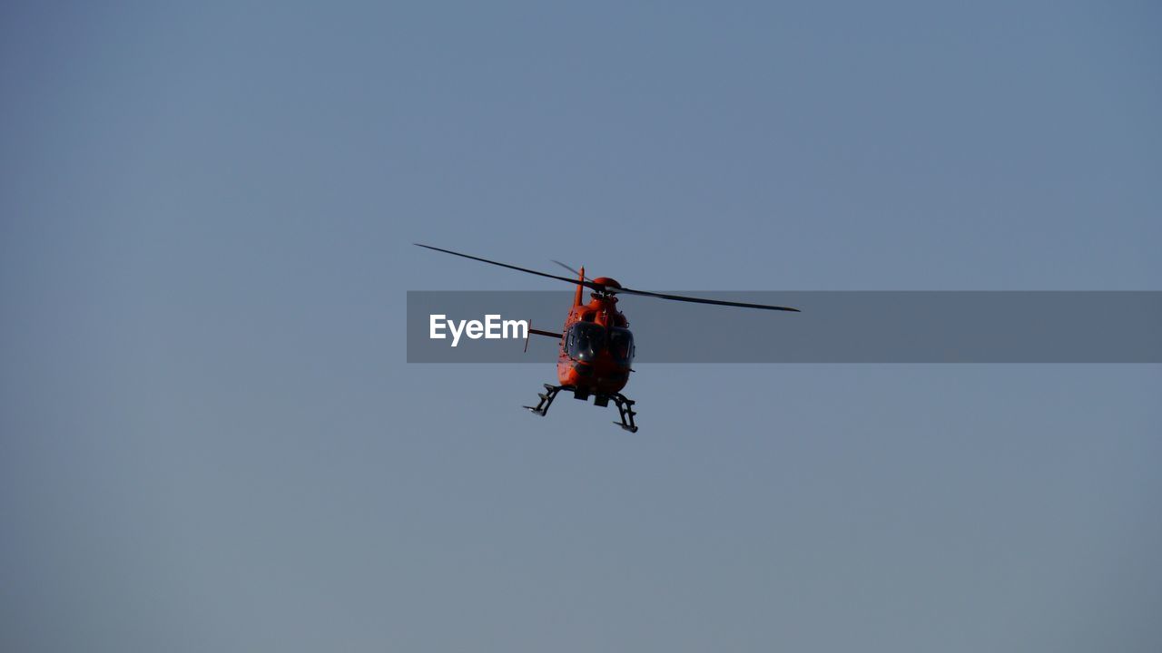 Low angle view of helicopter flying in clear sky