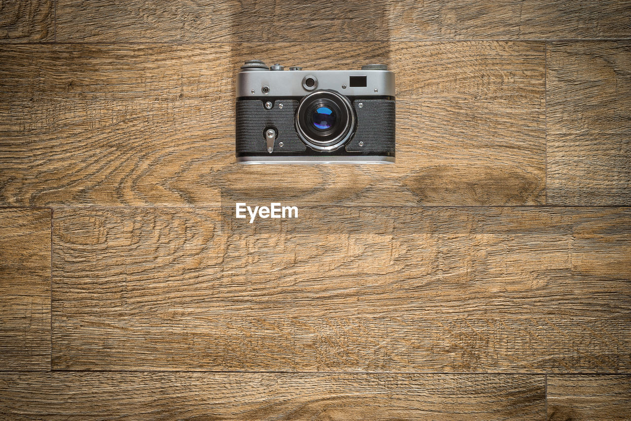 One old vintage photo camera on brown wooden background. top view with space for copy