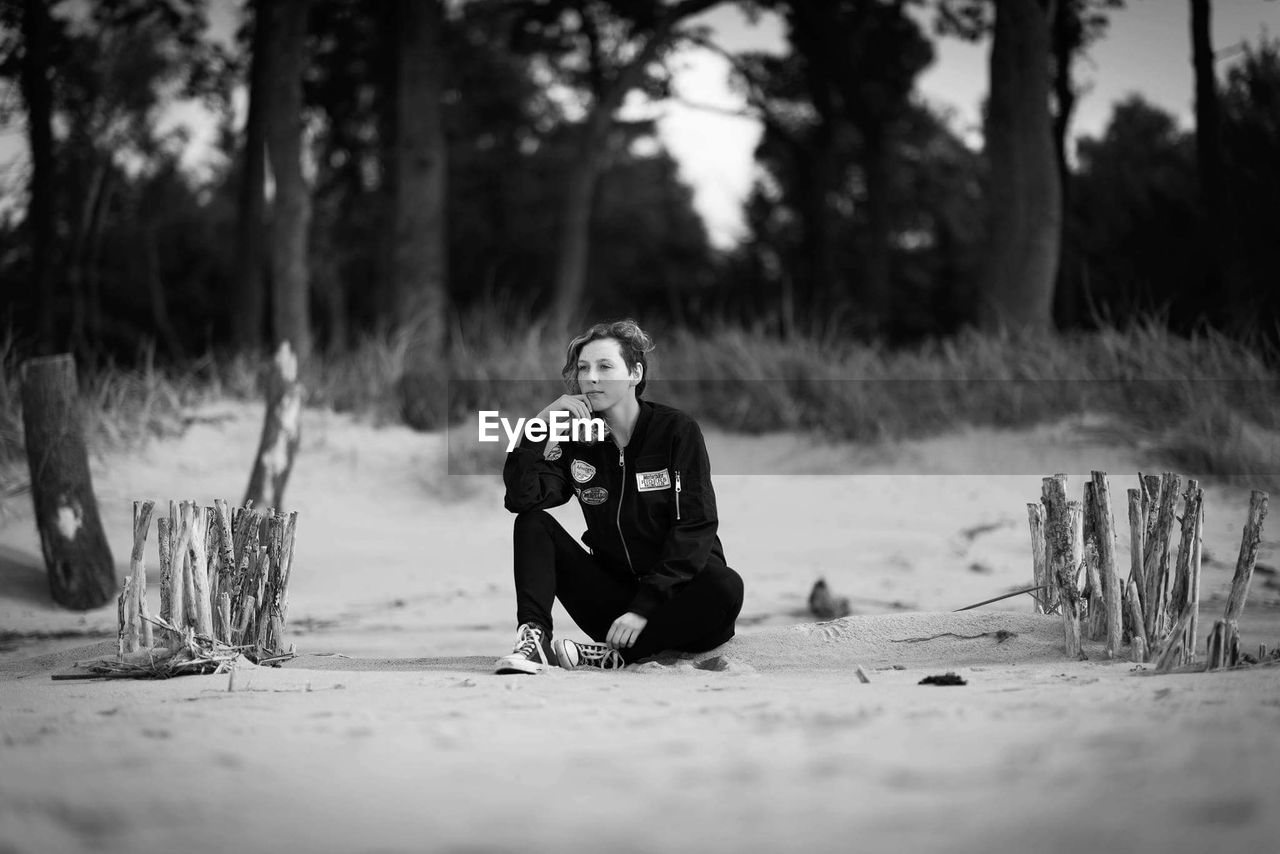 Young woman sitting on sand at beach