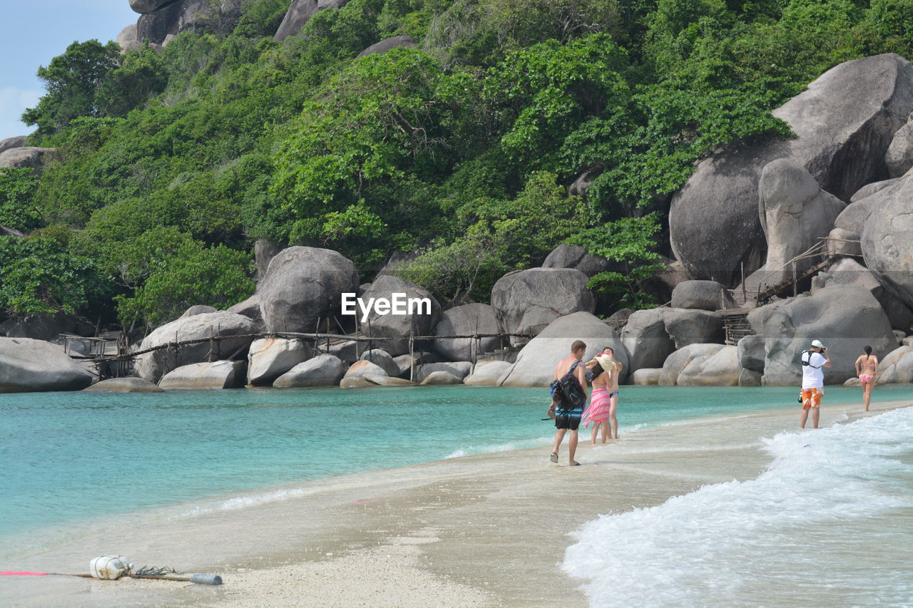 People enjoying at beach against mountain