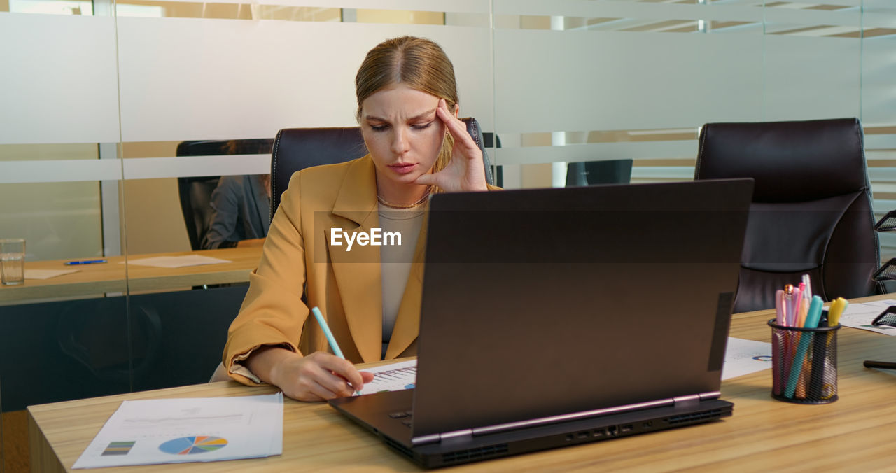 Businesswoman suffering from headache due to computer overwork. workaholic people concept.