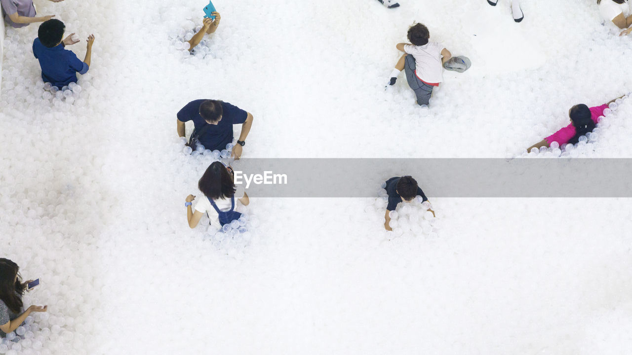 HIGH ANGLE VIEW OF PEOPLE ON SNOWCAPPED FIELD