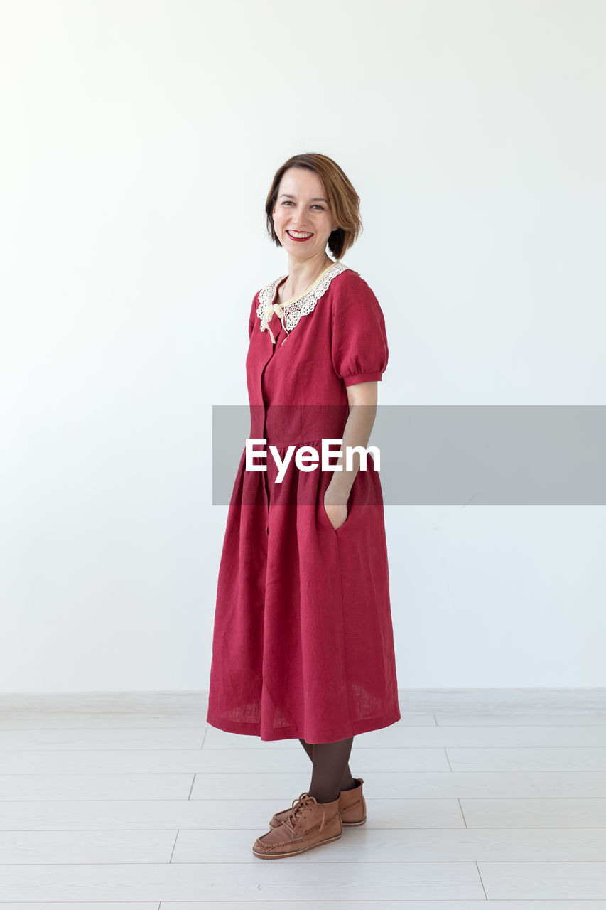 PORTRAIT OF A SMILING WOMAN STANDING ON FLOOR