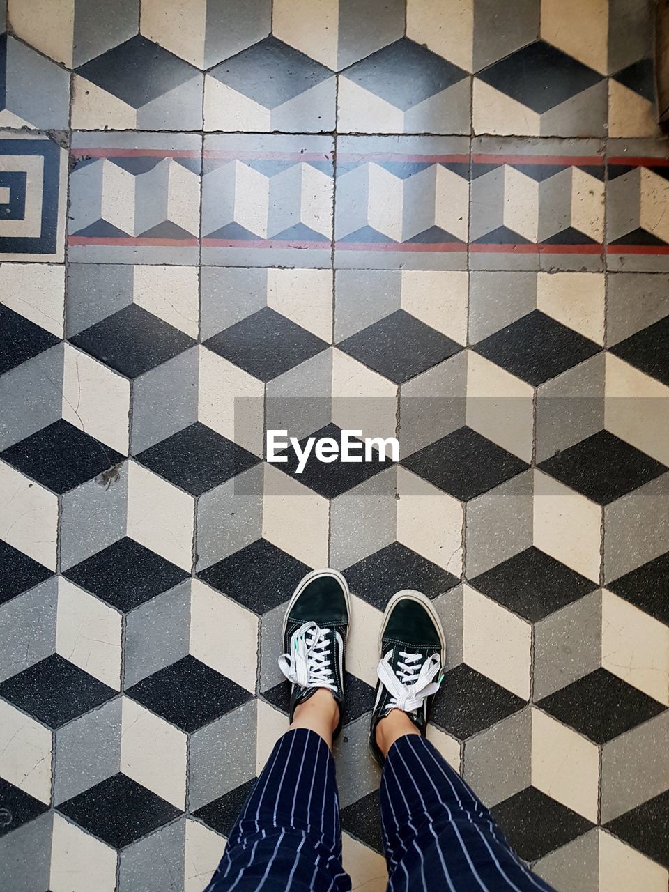 LOW SECTION OF WOMAN STANDING ON TILED FLOORING