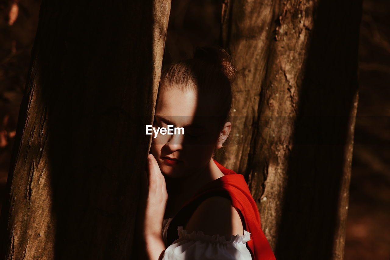 Woman in red riding hood amidst trees in forest