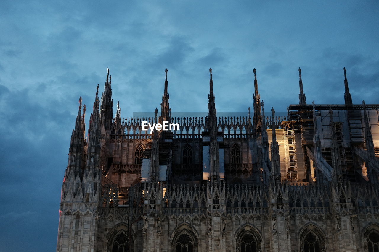 Low angle view of milan cathedral against cloudy sky at dusk