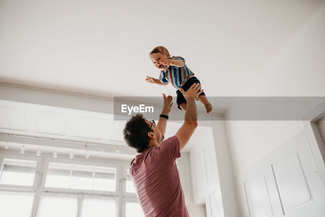 Low angle view of playful father catching son at home
