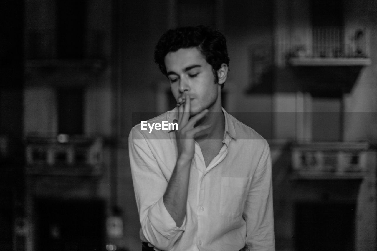 Young man smoking cigarette at home