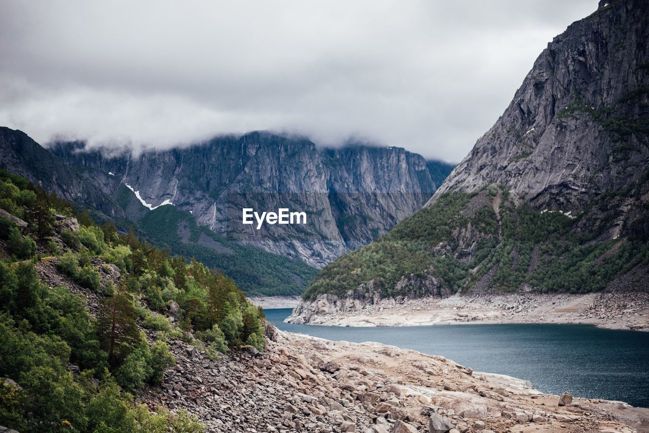 Scenic view of river amidst mountains against cloudy sky