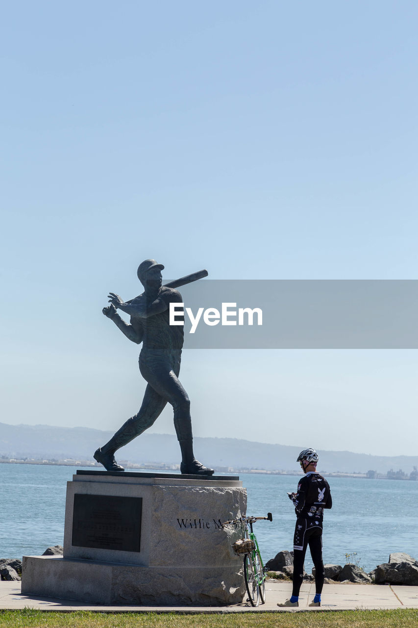 MAN STATUE AGAINST SEA AND CLEAR SKY