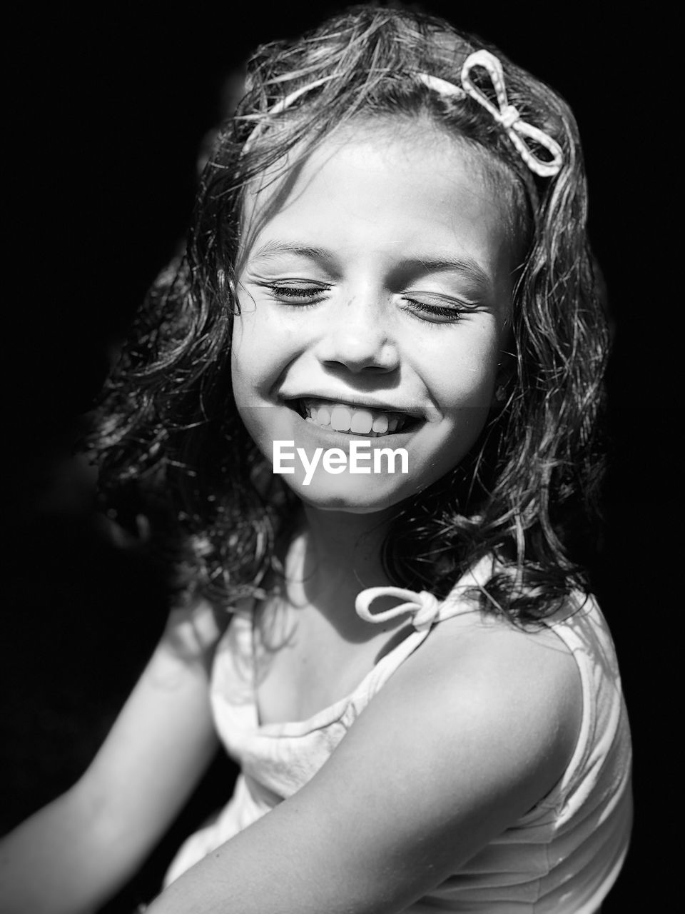 Smiling girl with eyes closed against black background