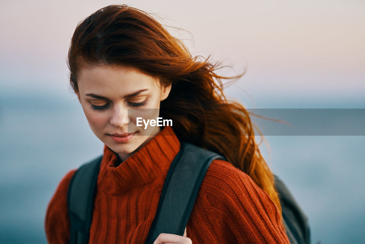 PORTRAIT OF YOUNG WOMAN AGAINST SKY