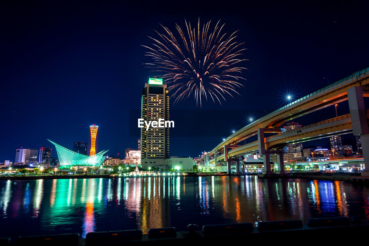 FIREWORK DISPLAY OVER RIVER BY BUILDINGS AGAINST SKY