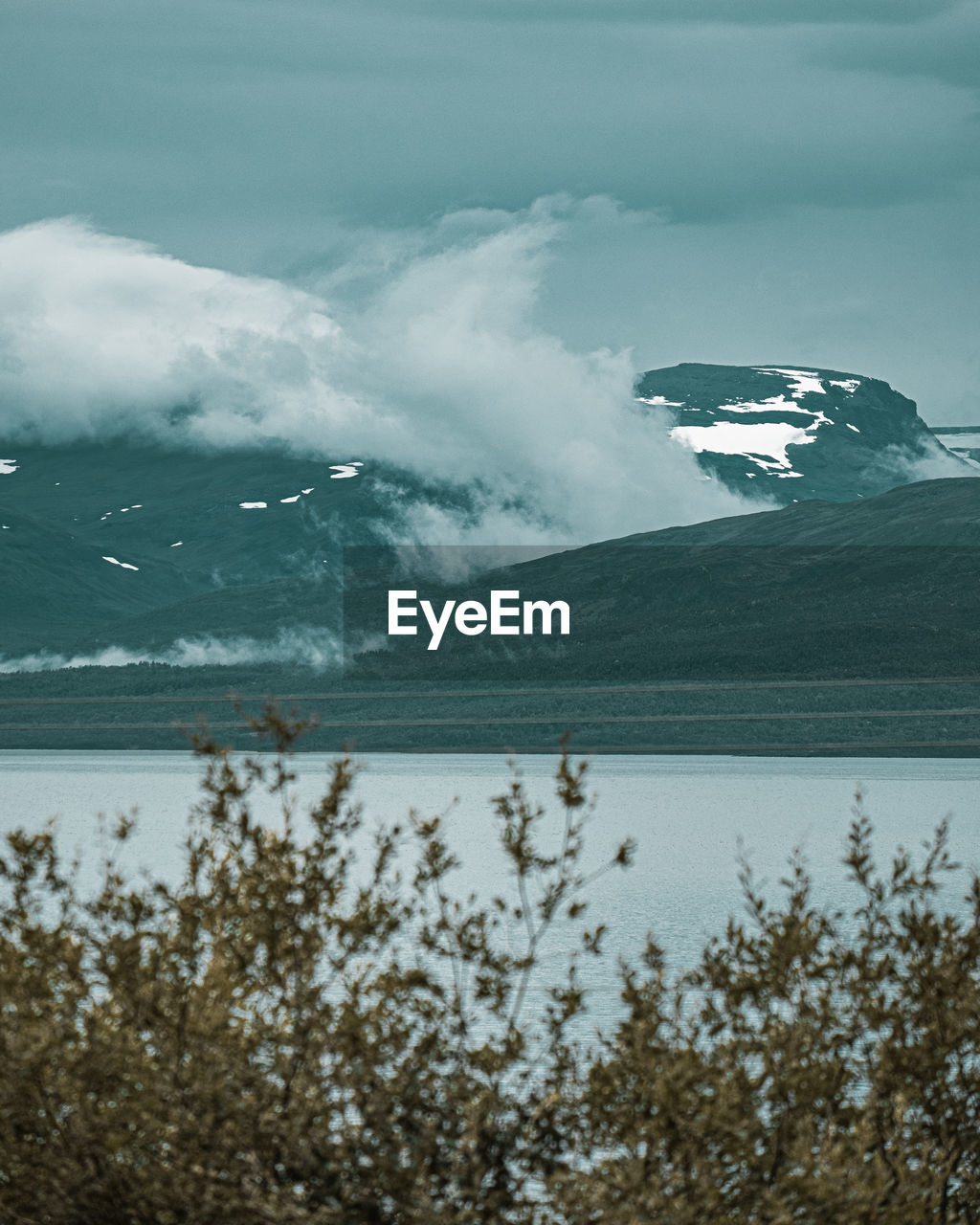 Scenic view of sea by snowcapped mountains against sky