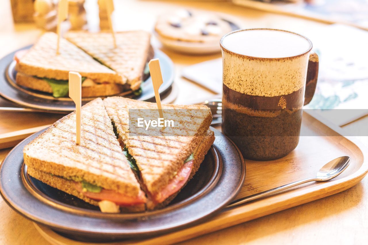 Close-up of toasted sandwiches with coffee on tray at table