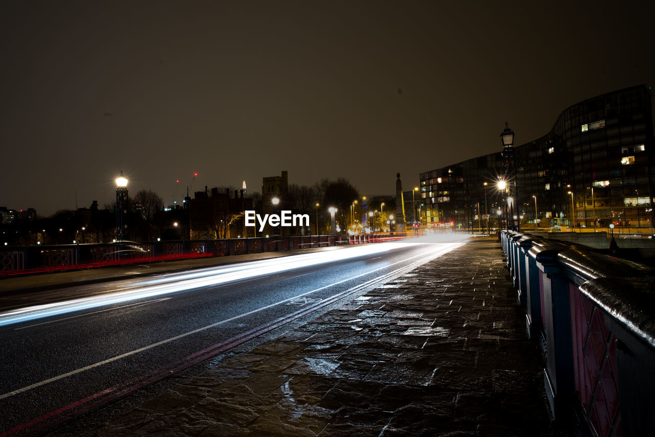 Light trails over street against sky at night in city