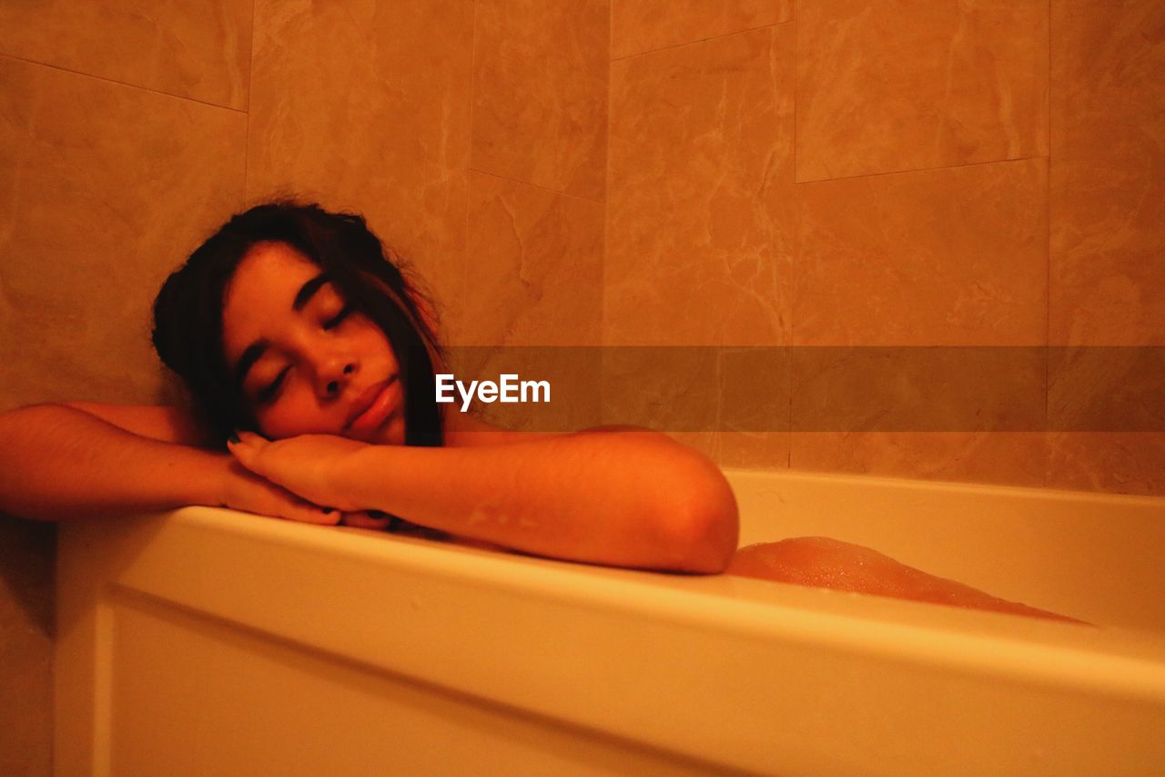 PORTRAIT OF WOMAN RELAXING IN BATHTUB
