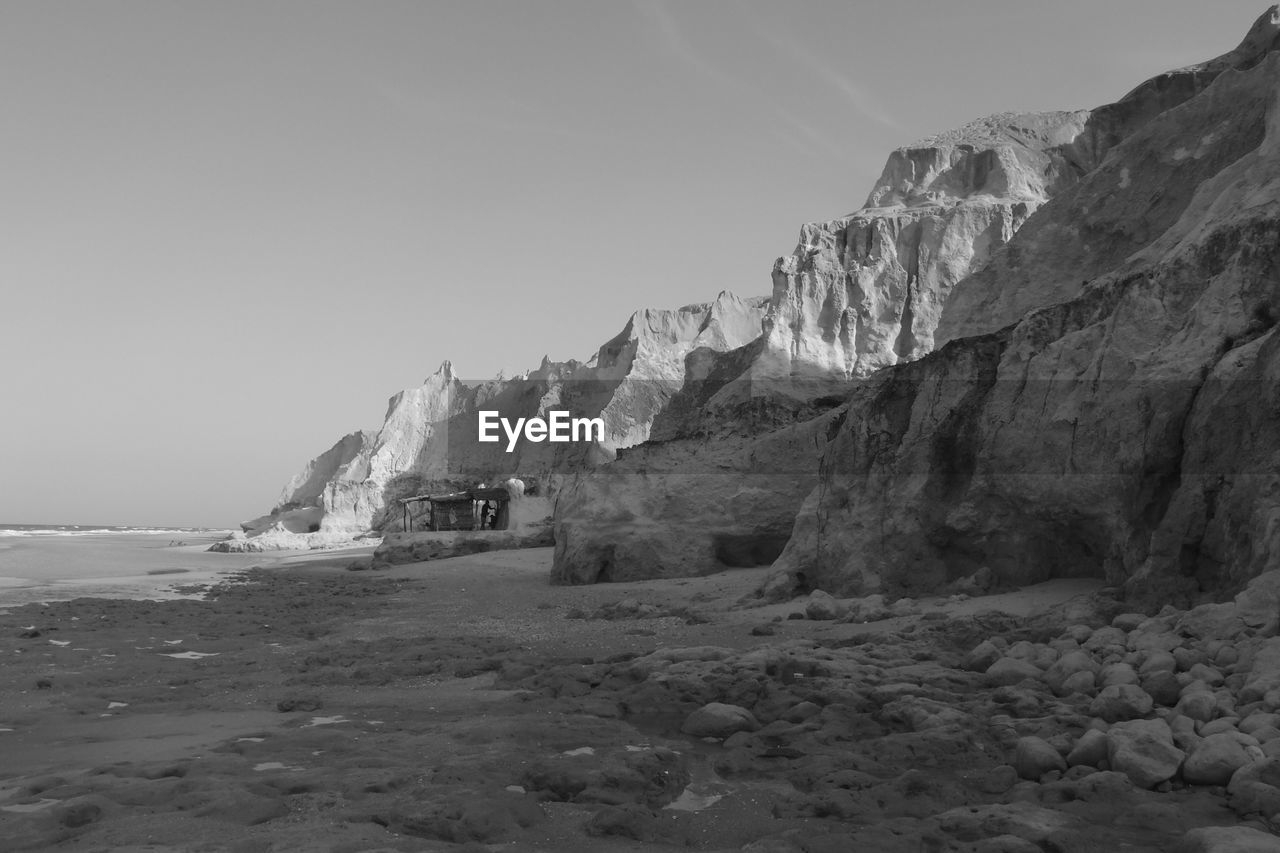 Scenic view of mountain by sea against clear sky