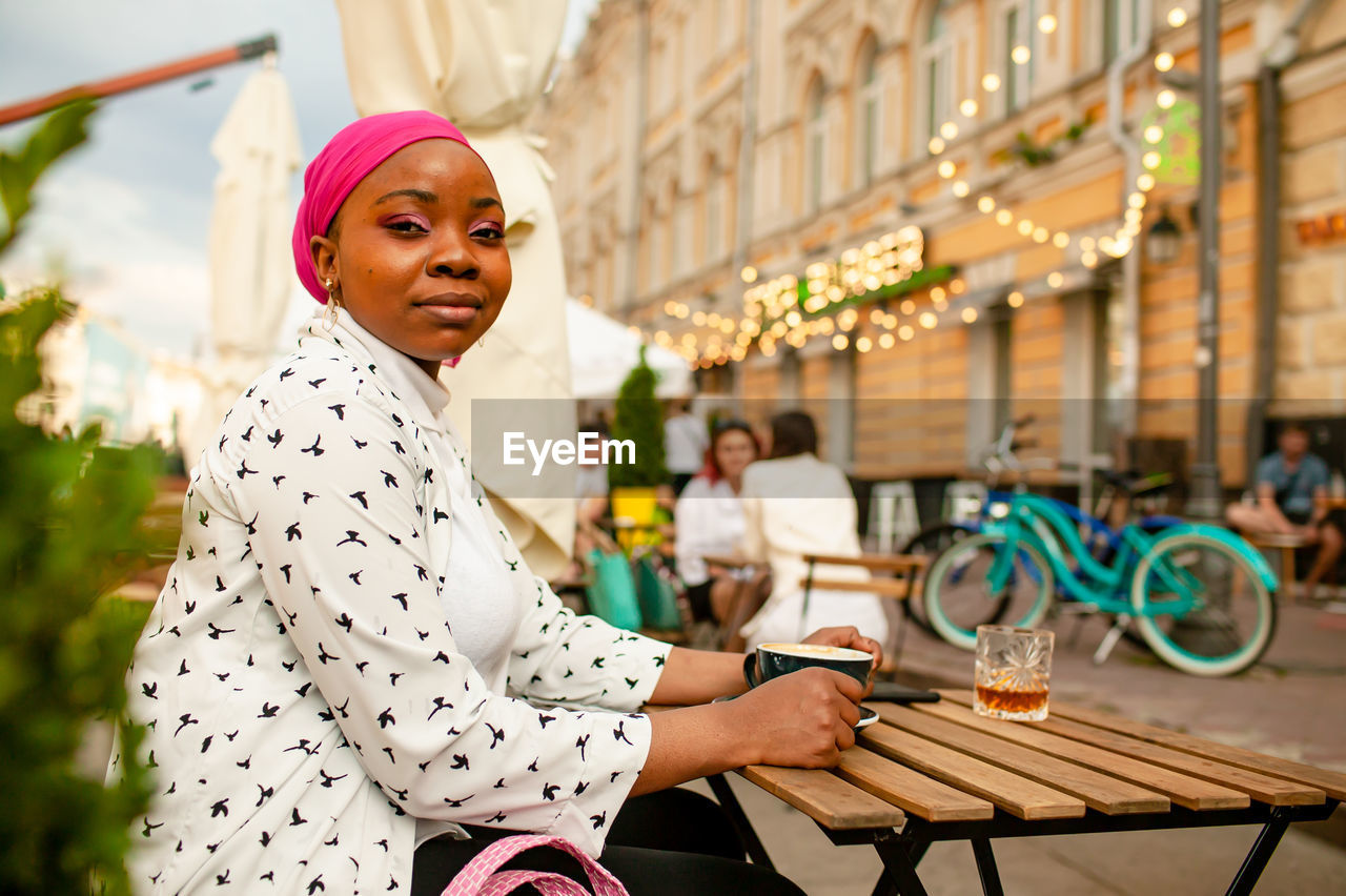 Young african muslim woman sitting in outdoor cafe