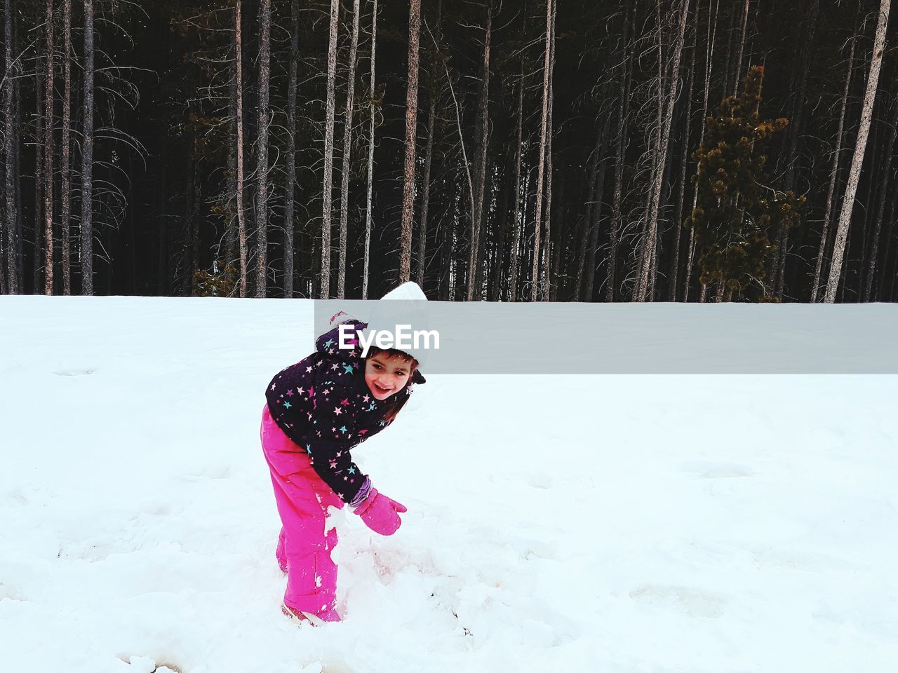 Girl playing with snow against trees