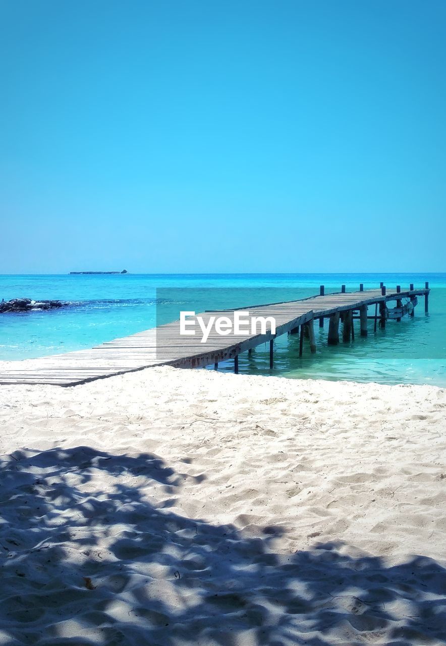 Scenic view of beach against clear blue sky