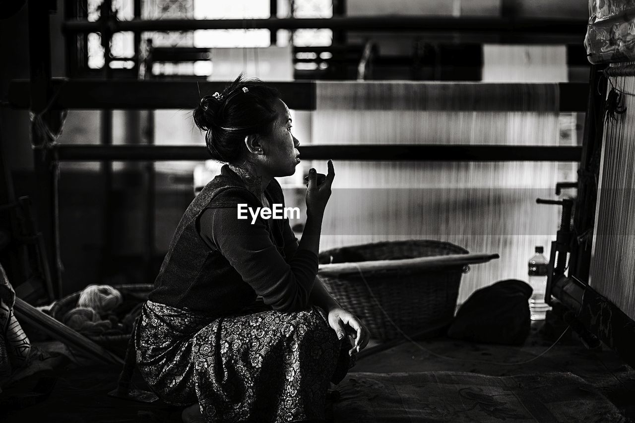 SIDE VIEW OF YOUNG WOMAN SMOKING OUTDOORS