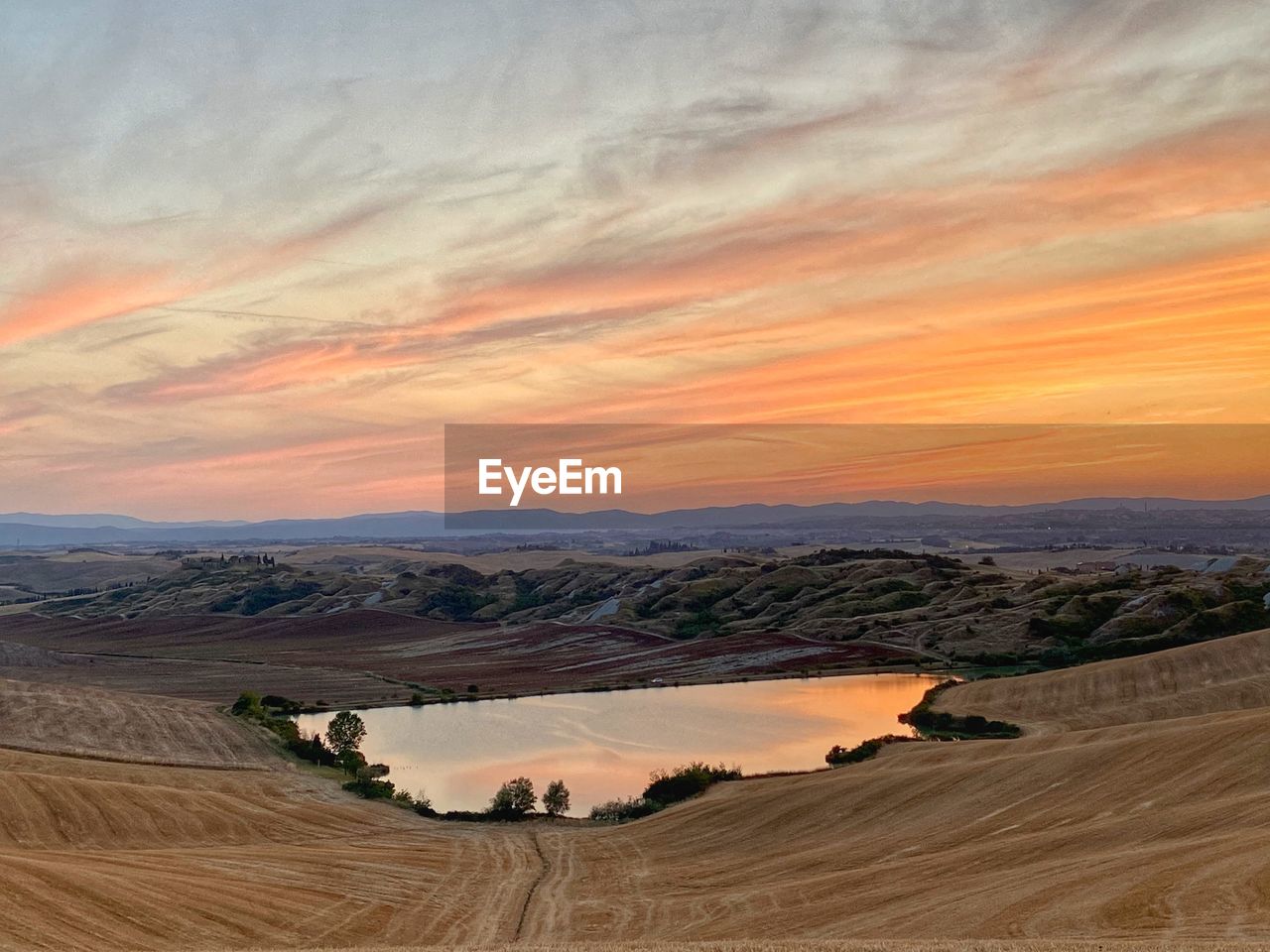 Scenic view of sunset colors reflections in a lake in tuscany 