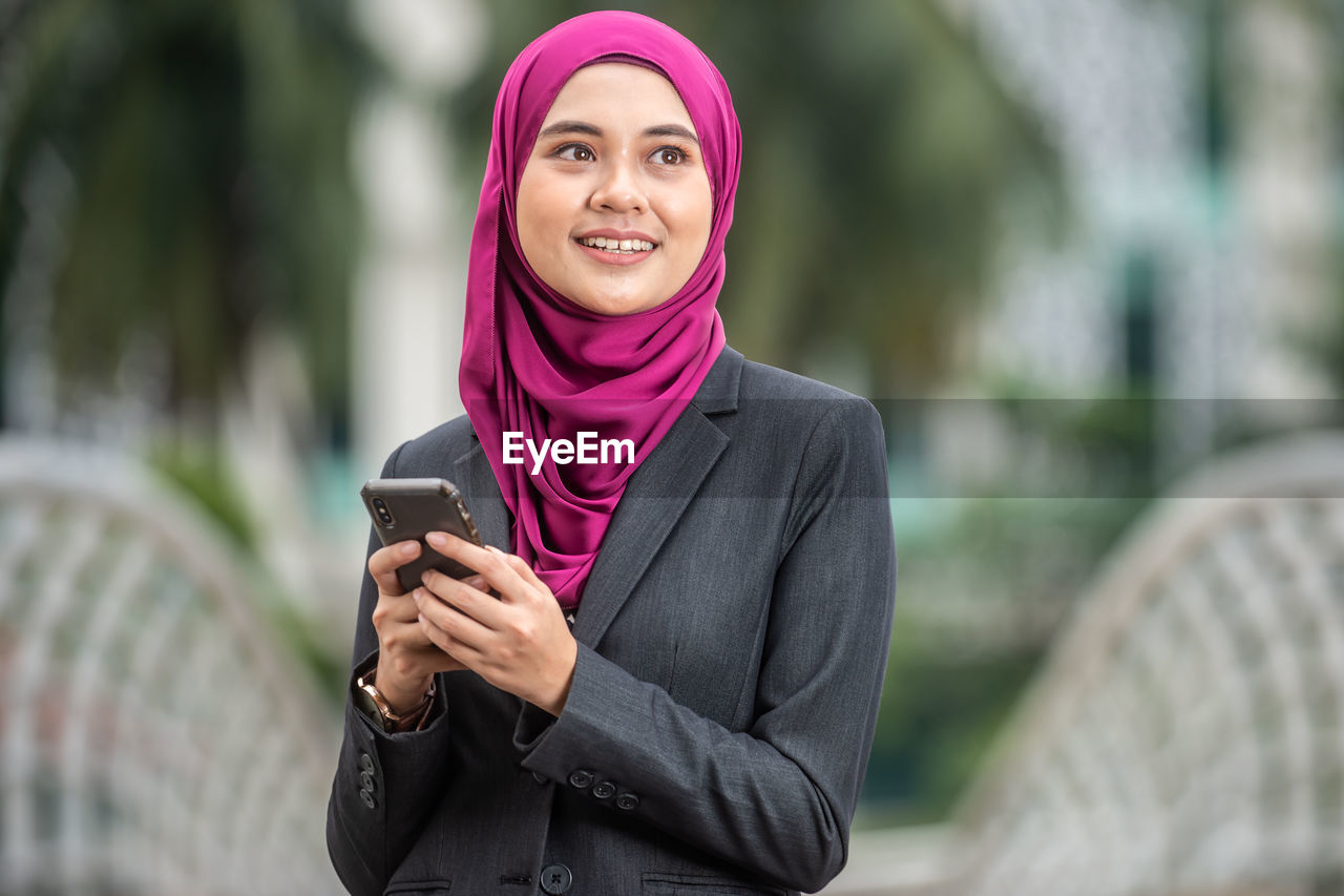 Young businesswoman wearing hijab using smart phone