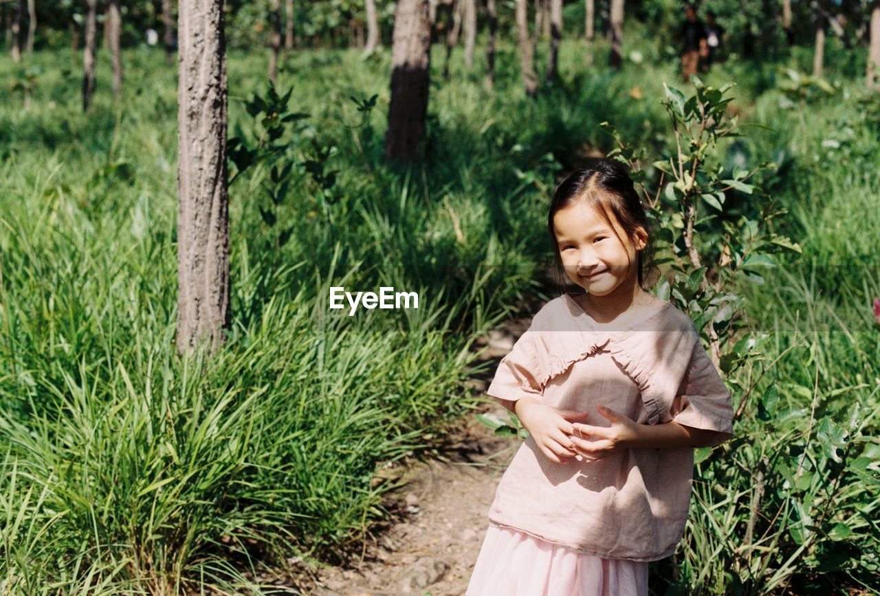 Smiling girl standing by plants