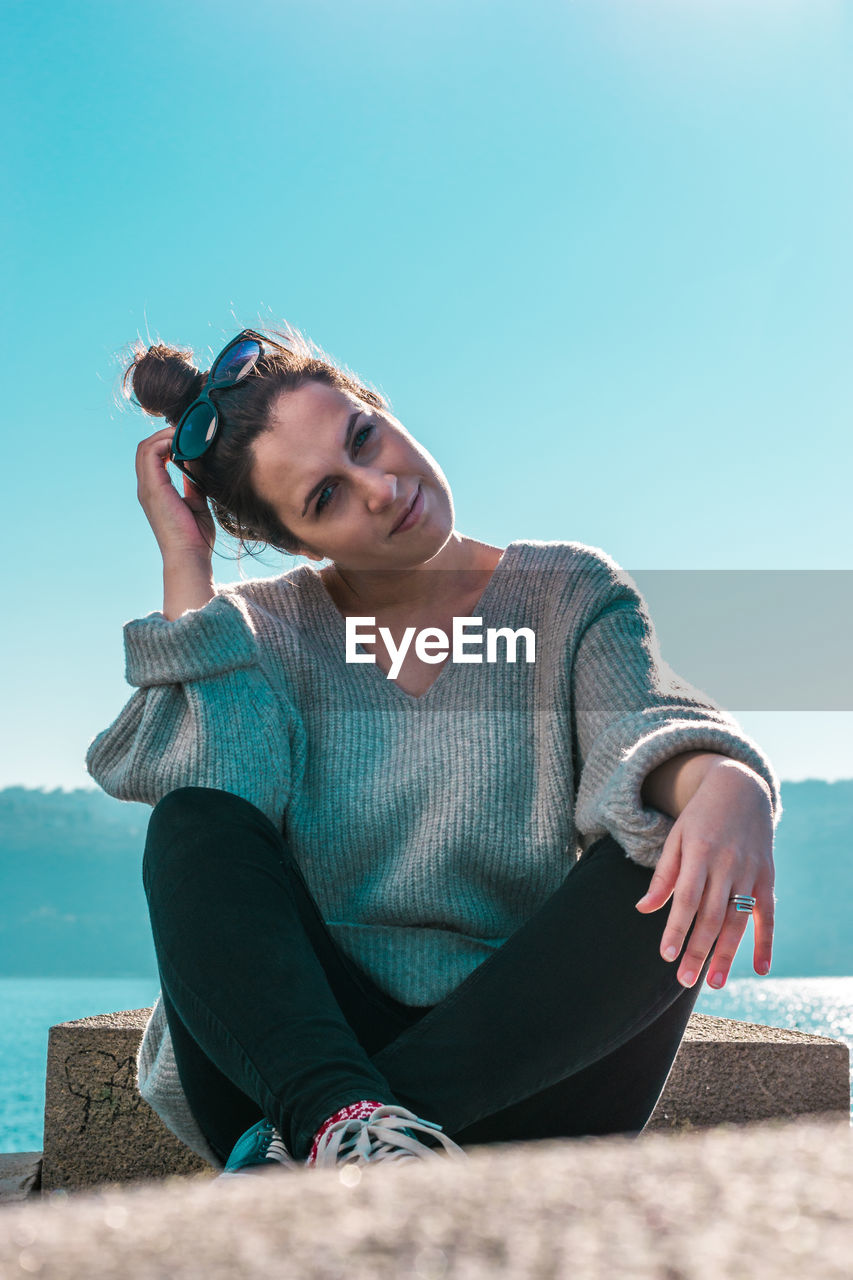 Portrait of woman sitting against sky