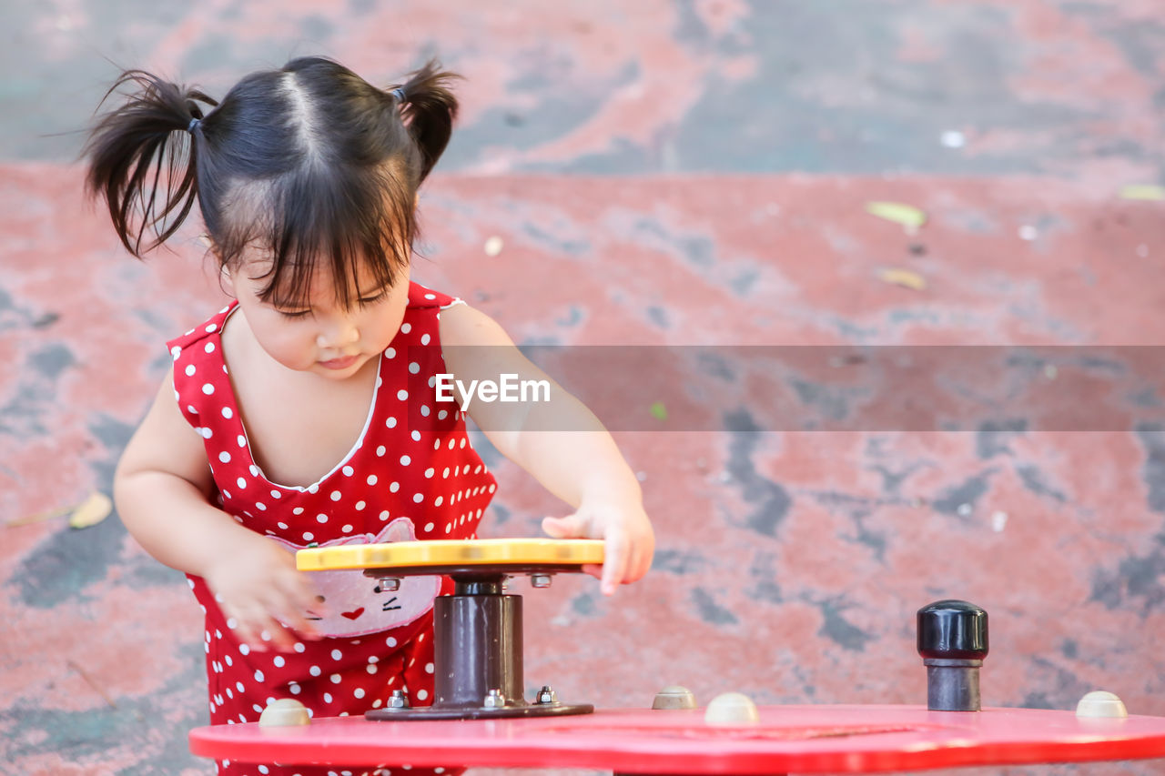 Cute girl playing yellow toy garlands on the playground