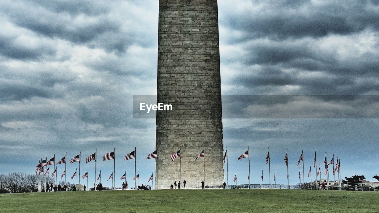 Low angle view of cemetery on field against cloudy sky