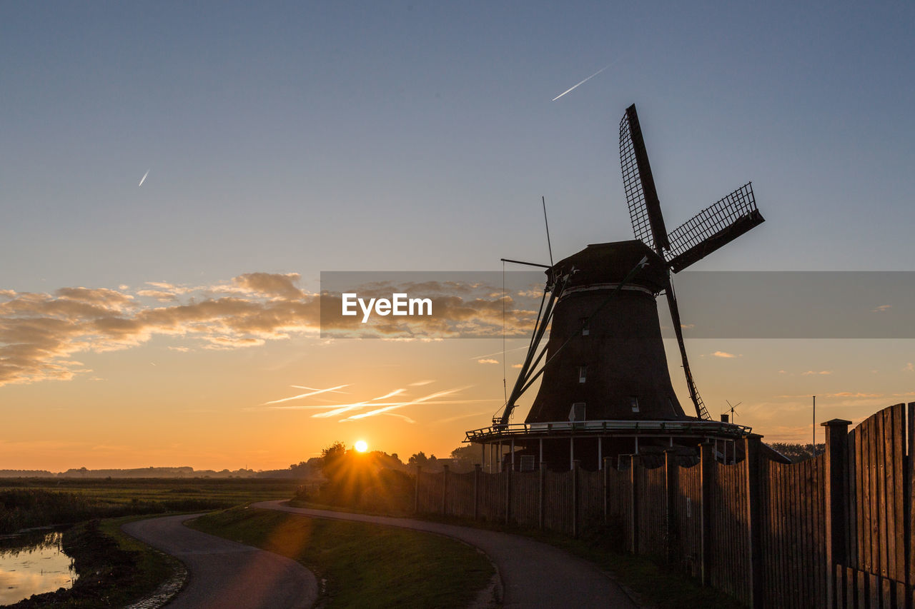 Traditional windmill against sky during sunset