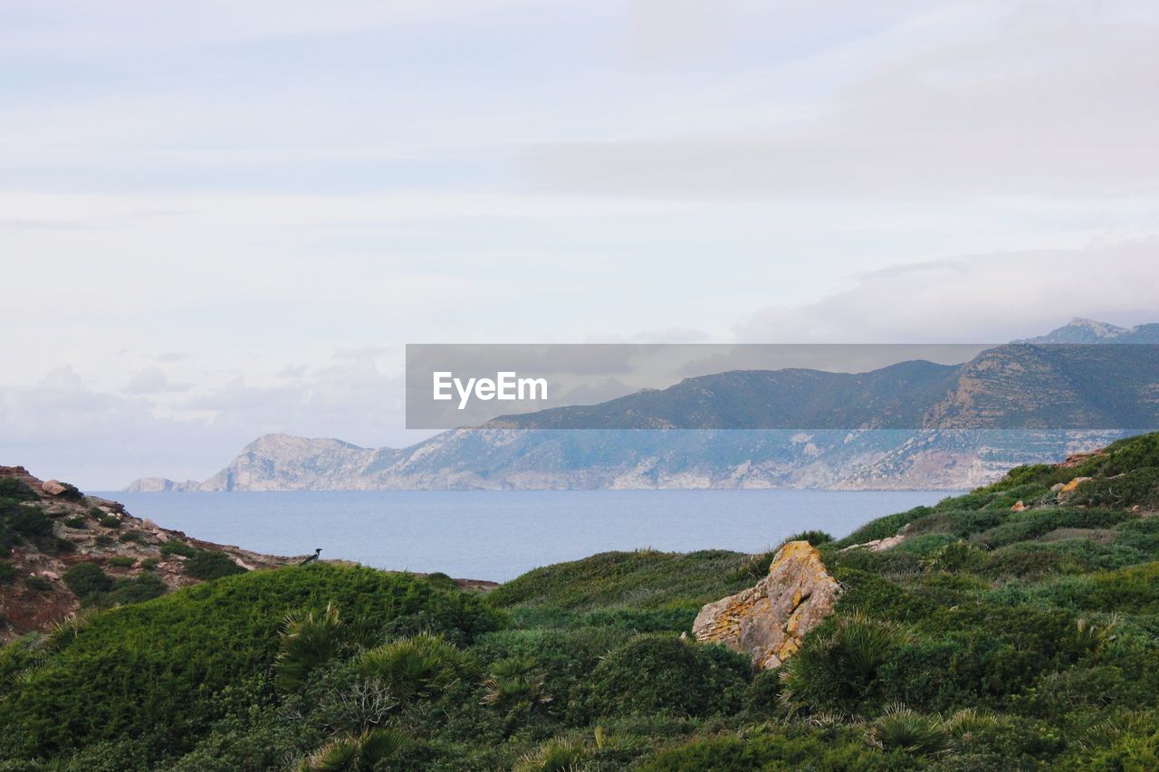 SCENIC VIEW OF MOUNTAINS AND SEA AGAINST SKY