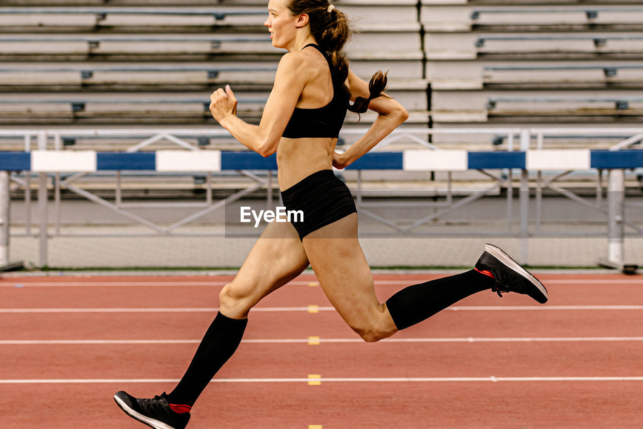 full length of young woman exercising on playing field