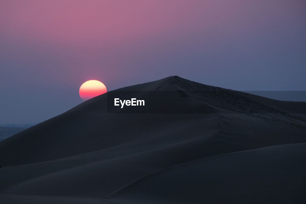 Low angle view of mountain against sky at sunset