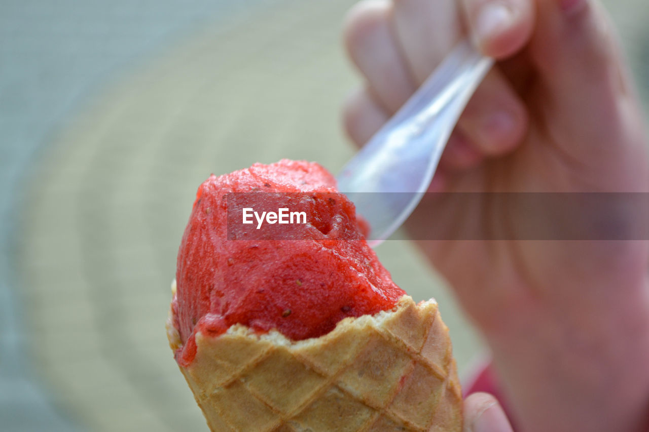 Holding fresh waffle cone with raspberry ice cream