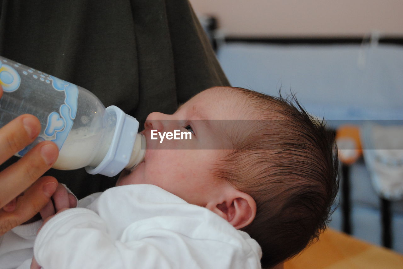 Midsection of mother feeding baby at home