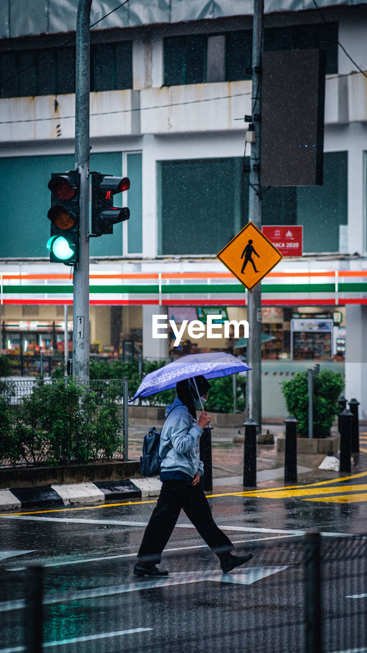 FULL LENGTH OF MAN WALKING ON WET STREET