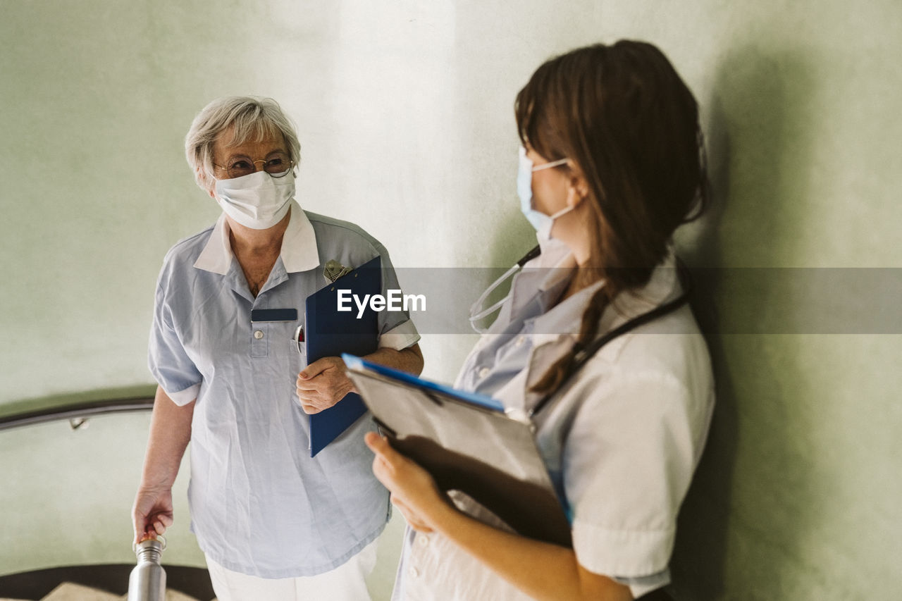 Female healthcare workers wearing face mask discussing at medical clinic during covid-19